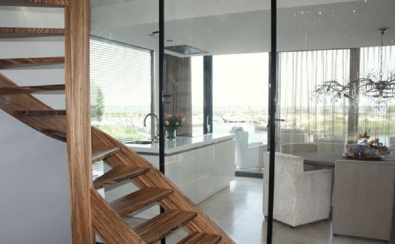Houten trap en glaswand in een watervilla in Harderwijk